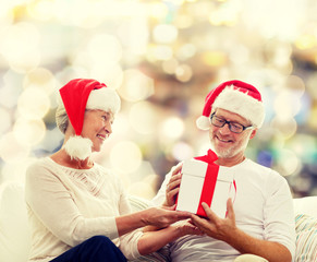 Fototapeta premium happy senior couple in santa hats with gift box