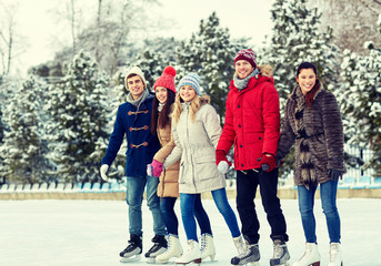 happy friends ice skating on rink outdoors