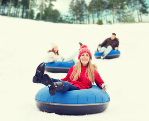 group of happy friends sliding down on snow tubes