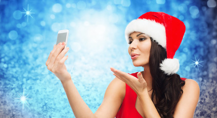 woman in santa hat taking selfie by smartphone