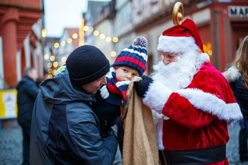 Little toddler boy with father and Santa Claus on Christmas market