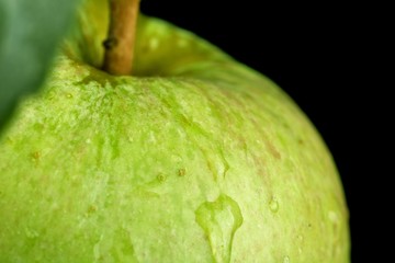 Macro closeup shot of drizzled green apple on black