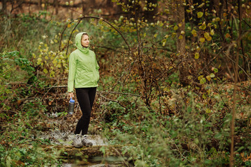 woman taking water from forest spring on hiking trip