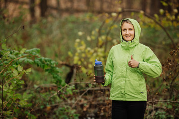 woman taking water from forest spring on hiking trip showing thu