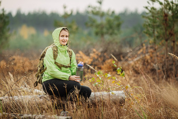 Naklejka na ściany i meble young woman drinking water with backpack at forest valley