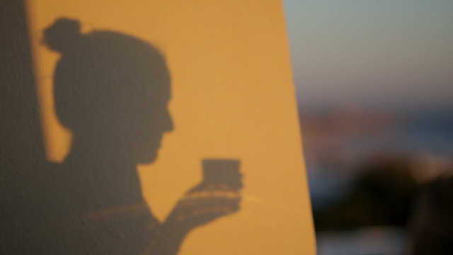 shadow silhouette of a woman drinking beverage from glass