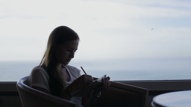 silhouette of young beautiful girl sits in a cafe with panoramic