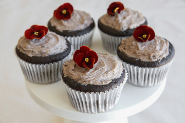 Homemade chocolate cupcakes with cookie and cream frosting and edible flower
