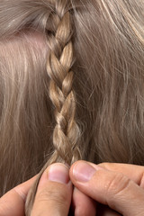 hands of hairdresser weaving braid her client
