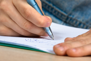 hands of child drawing in notebook