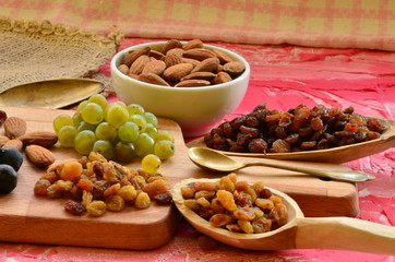 Various raisins, vine berries and almonds on chopping board
