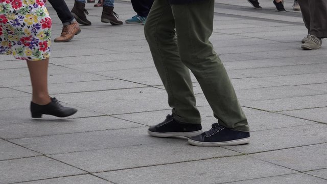 street dancers legs perform lindy hop dance step on street pedestrian pavement tiles. Street music day. Static shot. 4K
