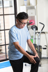 asian senior with knee injury during a gym workout