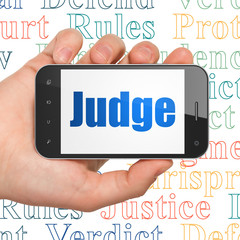 Law concept: Hand Holding Smartphone with Judge on display