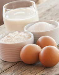 Ingredients for pancakes - eggs, flour, milk on wooden background.