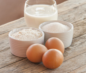 Ingredients for pancakes - eggs, flour, milk on wooden background.