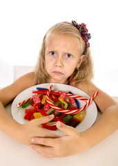 pretty sad Caucasian female child eating dish full of candy in sweet sugar abuse dangerous diet