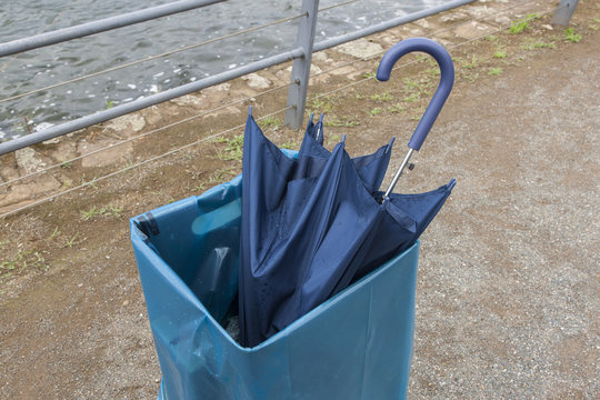 Regenschirm in der Mülltonne