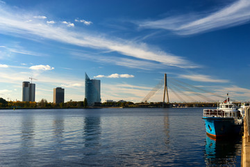 Fototapeta na wymiar Blue boat on the River Daugava in the background of a suspension