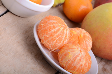 Bowls of slices mandarin with apple on rustic wooden background