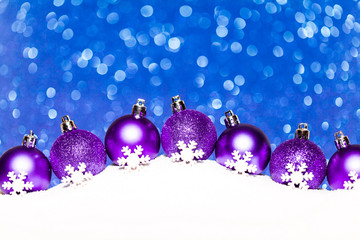 christmas purple balls in snow on blue glitter background