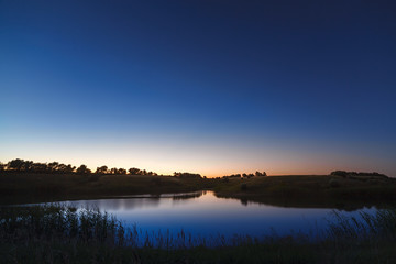 Morning dawn on a starry background sky reflected in the water o
