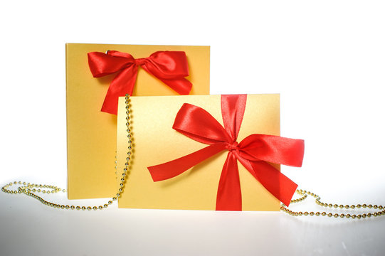 Golden gift wrapped present with red satin ribbon bow on white