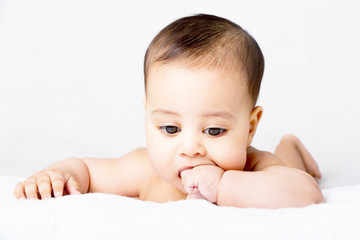 Sweet baby lying on bed and sucking his finger

