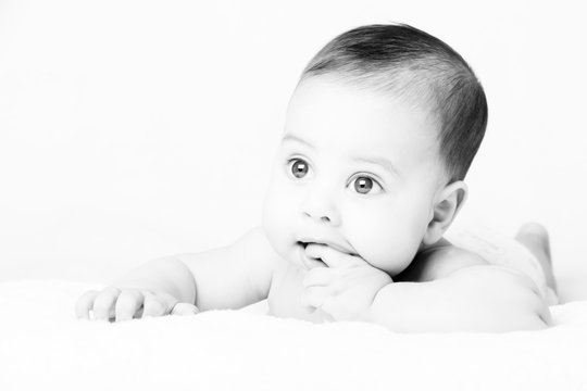 Cute baby lying on bed and sucking his finger - High Key
