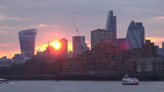 London skyline at sunset with tour boat on river Thames

