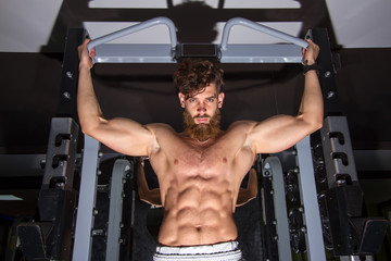 Fototapeta na wymiar Muscular man with the beard training in the gym