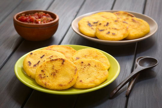 Colombian arepas made of corn meal with hogao sauce (tomato and onion cooked) in the back (Selective Focus, Focus on the first arepas)
