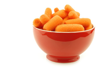 prepared carrots in a red ceramic bowl on a white background