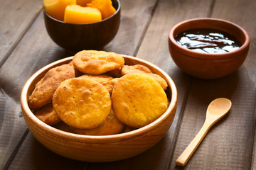 Traditional Chilean Sopaipilla fried pastry, served with Chancaca sweet sauce, photographed with natural light (Selective Focus, Focus on the first two sopaipillas) © Ildi