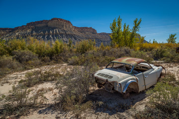 Classic Old Car decays in a meadow. 
