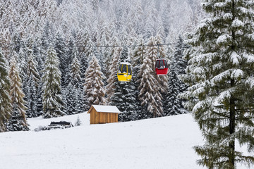 Snowy forest and colorful gondola cabins, Dolomites, Italy