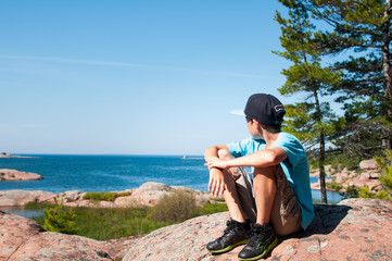 boy sitting on a rock during a hike in Killarney Provincial Park Ontario Canada