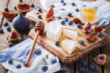 Obraz na płótnie Canvas Brie cheese,Camembert with Ingram,blueberries and honey on a wooden Board.selective focus