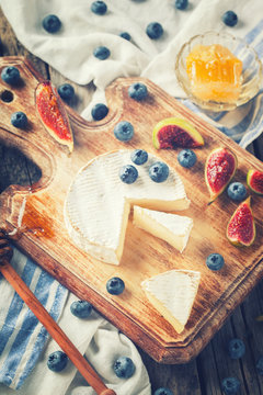 Brie cheese,Camembert with Ingram,blueberries and honey on a wooden Board. Toned image. Vintage styleselective focus