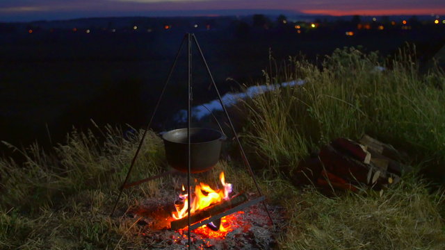 4 in 1 video! The cauldron with food on the fire by picturesque landscape background. Shot with Red Cinema Camera