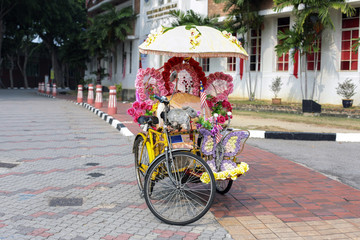 Fototapeta na wymiar Trishaw decorated with colorful flowers in Malacca, Malaysia.