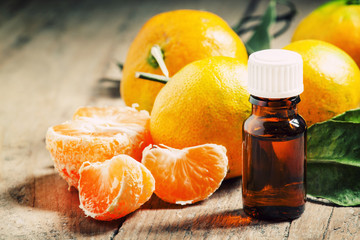 Aromatic tangerine oil, with tangerines on a wooden background,