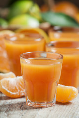 Fresh tangerine juice with slices of mandarin on old wooden back