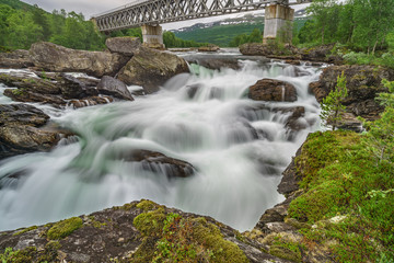 Fototapeta na wymiar A railway bridge spans an impressive waterfall in northern Norway