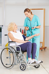 Seniorin bekommt Blutdruck gemessen im Pflegeheim