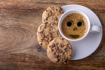cup of coffee with chocolate cookies on wood