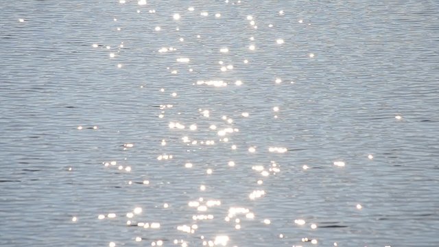 Blue water surface with waves and sparkles glitters in the sun