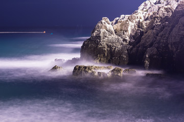 Sea waves lash line impact rock on the beach in night