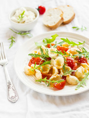 Orecchiette pasta with cherry tomatoes, arugula and Parmesan for a bright plate on a white surface