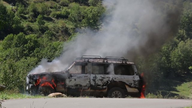 Burning car in the middle of nature, at the moment which exploits a wheel.